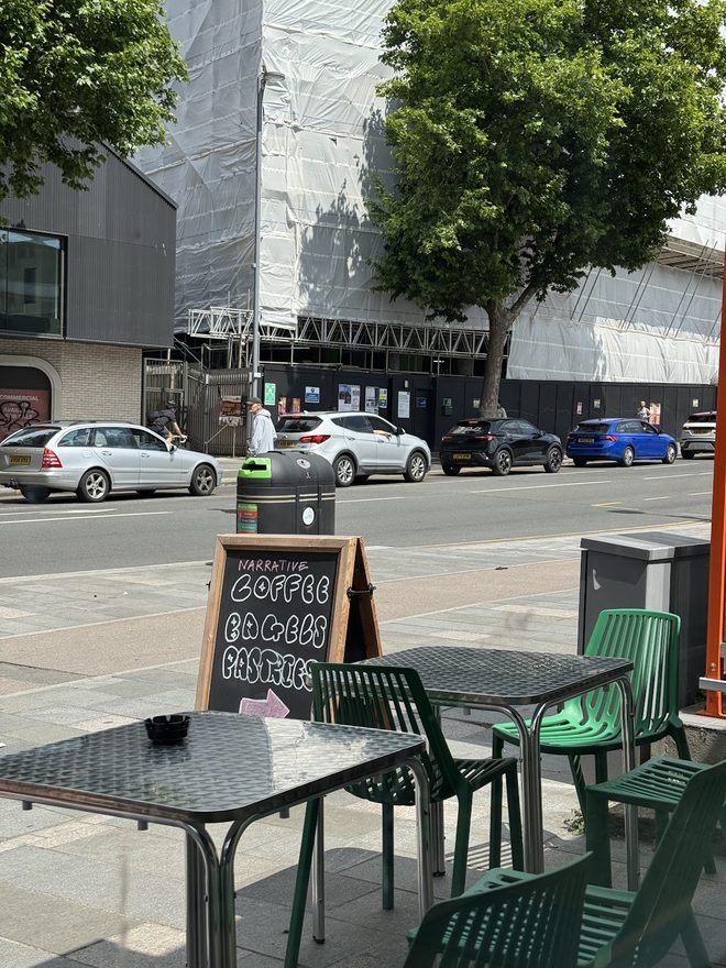 Outdoor tables and green chairs on the footpath outside the cafe
