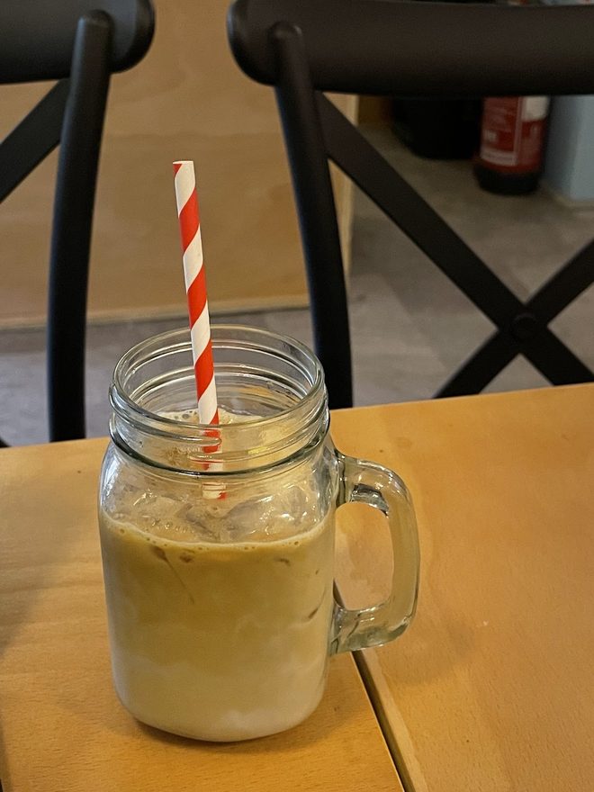 An iced latte in a mason jar mug on a wooden table