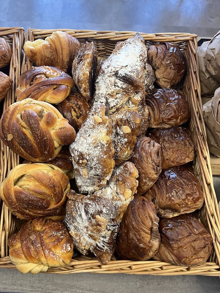 Cinnamon buns and almond croissants in a wicker basket