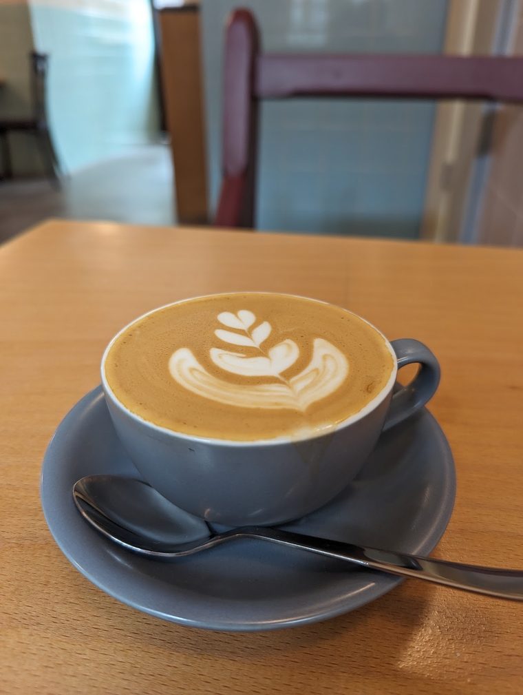 A flat white with rosetta latte art in a blue cup